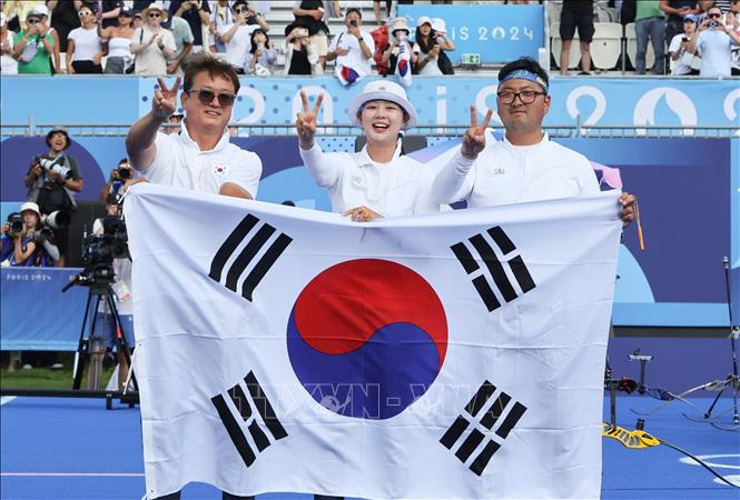 Bộ đôi cung thủ Lim Si-hyeon (giữa) và Kim Woo-jin (phải) của Hàn Quốc giành Huy chương Vàng môn bắn cung đồng đội phối hợp nam nữ tại Olympic Paris 2024, ngày 2/8/2024. Ảnh: YONHAP/TTXVN