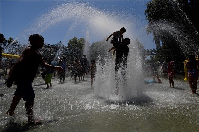 Người dân làm mát bên đài phun nước trong ngày nắng nóng gay gắt ở hạt Orange, California, Mỹ ngày 22/6/2024. Ảnh: THX/TTXVN