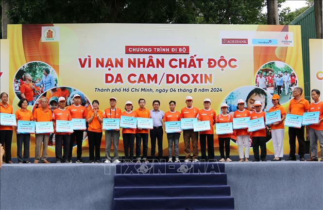 Phó Chủ tịch UBND Thành phố Hồ Chí Minh Trần Thị Diệu Thúy cùng đơn vị tài trợ trao sổ tiết kiệm cho các gia đình, nạn nhân da cam. Ảnh: Thanh Vũ-TTXVN
