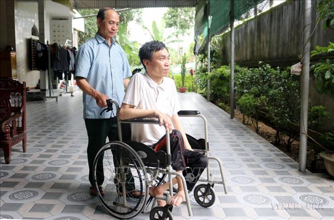 Thương binh Nguyễn Đình Duyên (bản Hốc, xã Châu Đình, huyện Quỳ Hợp, tỉnh Nghệ An) - Dũng sỹ diệt Mỹ, cùng đồng đội bắn rơi 6 máy bay địch trong một trận đấu, bên người con trai bị nhiễm chất độc da cam. Ảnh: Văn Tý-TTXVN