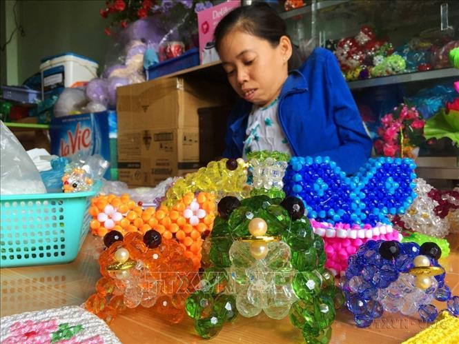 Chị Trần Kim Phượng (40 tuổi) ở phường Lê Bình, quận Cái Răng, thành phố Cần Thơ, nạn nhân chất độc da cam. Dù cơ thể tàn tật do nhiễm độc, sức khỏe yếu nhưng chị đã vượt lên hoàn cảnh, quyết vươn lên theo học nghề kết cườm, tạo việc làm có thu nhập cho bản thân. Ảnh: Thanh Liêm - TTXVN