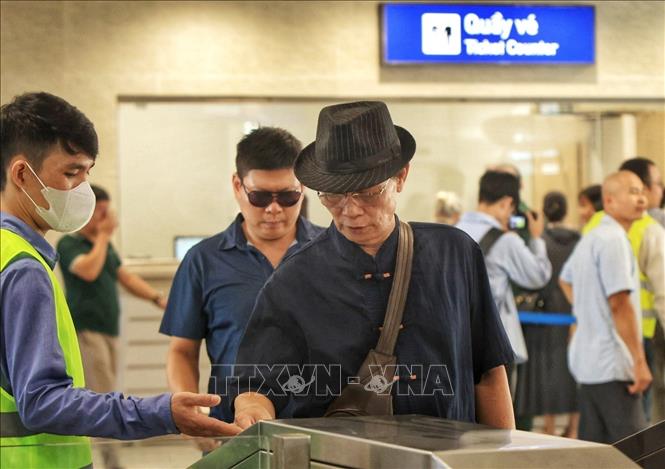 Hành khách quẹt thẻ lên tàu theo hướng dẫn của nhân viên. Ảnh: Tuấn Anh - TTXVN