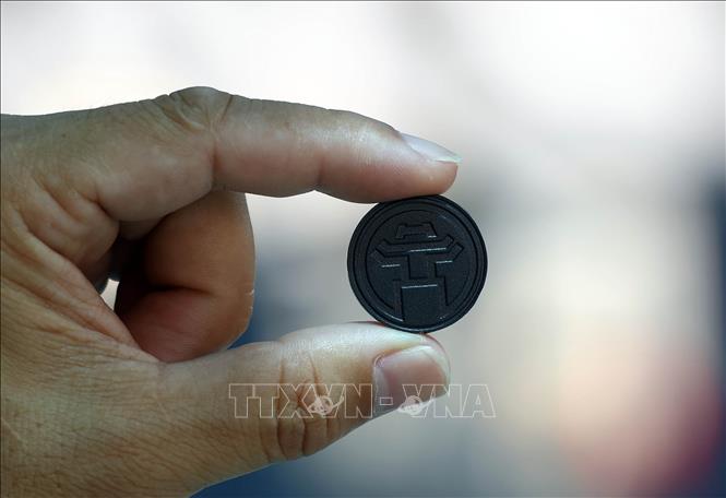 Vé tàu Metro Nhổn - Ga Hà Nội có thể dùng thẻ cứng hoặc dạng đồng xu để qua cửa soát vé. Vé hình đồng xu khắc biểu tượng Chùa Một cột. Ảnh: TTXVN