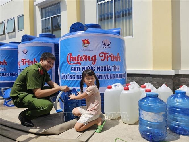 Cán bộ, chiến sĩ công an tỉnh Bến Tre hỗ trợ người dân xã An Định, huyện Mỏ Cày Nam lấy nước ngọt miễn phí về sinh hoạt do ảnh hưởng bởi hạn hán và xâm nhập mặn. Ảnh: Chương Đài - TTXVN