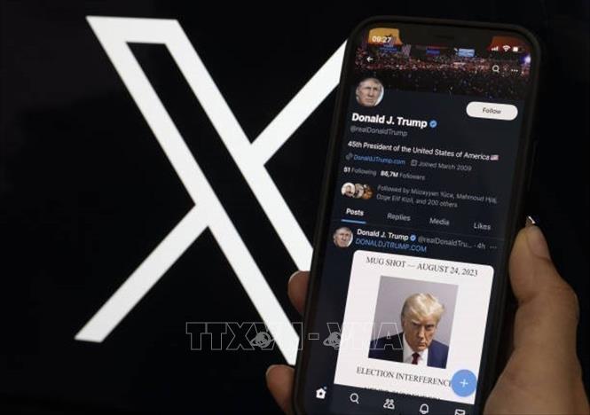 Tài khoản mạng xã hội X của cựu Tổng thống Mỹ Donald Trump trên màn hình điện thoại và biểu tượng mạng xã hội X (phía sau). Ảnh: Getty Images/TTXVN