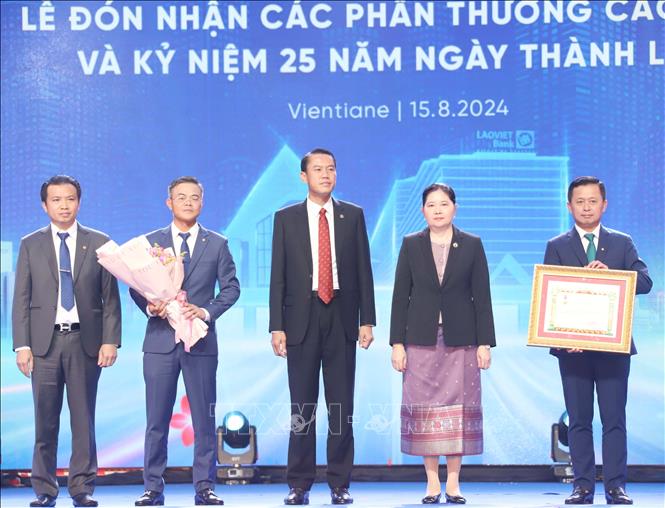 Quyền Thống đốc Ngân hàng Nhà nước Lào, bà Vathana Dalaloy (thứ hai, từ phải sang), thay mặt Nhà nước Lào trao tặng Huân chương Lao động hạng Nhất cho LaoVietBank. Ảnh: Xuân Tú - PV TTXVN tại Lào