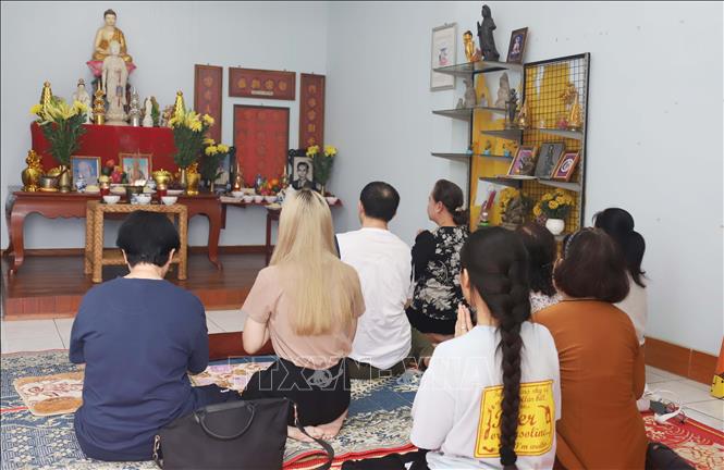 Bà Trần Thị Tuyết Anh cùng con cháu thực hiện nghi thức cúng gia tiên trong ngày Lễ Vu lan tại Lào. Ảnh: Xuân Tú - PV TTXVN tại Lào