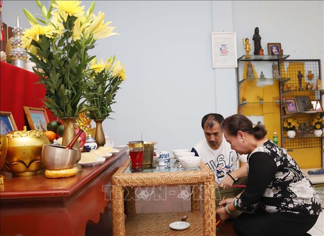 Bà Trần Thị Tuyết Anh hướng dẫn con cháu sắp đặt mâm cơm chay thờ cúng tổ tiên trong lễ Vu lan. Ảnh: Xuân Tú - PV TTXVN tại Lào