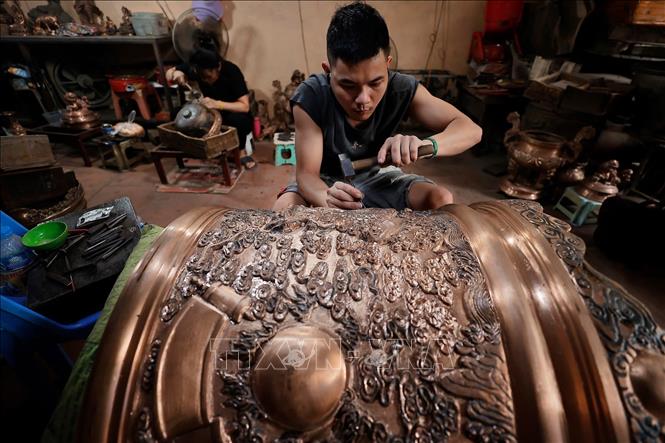 Nghệ nhân tỉ mỉ chạm khắc từng đường nét tinh xảo cho sản phẩm đồng đúc. Ảnh: Minh Quyết - TTXVN