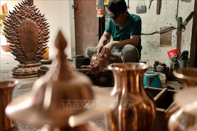 Nghệ nhân tỉ mỉ chạm khắc từng đường nét tinh xảo cho sản phẩm đồng đúc. Ảnh: Minh Quyết - TTXVN