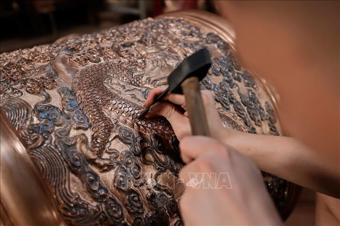 Tỉ mỉ chạm khắc từng đường nét tinh xảo cho sản phẩm đồng đúc. Ảnh: Minh Quyết - TTXVN