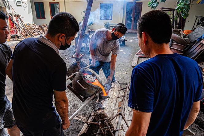 Quá trình rót đồng vào khuôn được người thợ thực hiện cẩn thận. Ảnh: Phạm Tuấn Anh - TTXVN