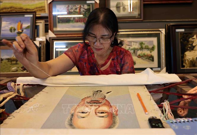 Nghệ nhân Lê Thị Xuân đang hoàn thiện bức tranh thêu tay chân dung Chủ tịch Hồ Chí Minh. Ảnh: Trần Việt - TTXVN
