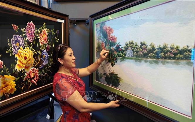 Nghệ nhân Lê Thị Xuân tâm đắc với bức tranh thêu phong cảnh Hồ Hoàn Kiếm. Ảnh: Trần Việt - TTXVN
