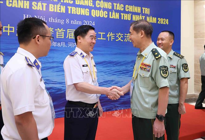 Lieutenant General Bui Quoc Oai, Political Commissar of the VCG, welcomes Major General Liu Houjie, Deputy Political Commissar of the CCG. VNA Photo: An Đăng 