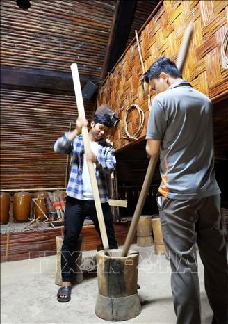 Du khách trải nghiệm giã gạo chày đôi trong nhà dài truyền thống của người S’tiêng. Ảnh: Hồng Đạt - TTXVN
