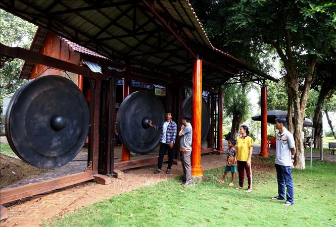 Du khách tìm hiểu bộ cồng chiêng lớn nhất Việt Nam trưng bày trong Khu bảo tồn văn hóa dân tộc S’tiêng sóc Bom Bo. Ảnh: Hồng Đạt - TTXVN
