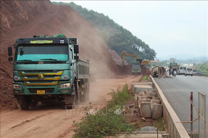 Các nhà thầu huy động máy, nhân công xử lý phần nền, móng để rải thảm nhựa. Ảnh: Quang Duy - TTXVN