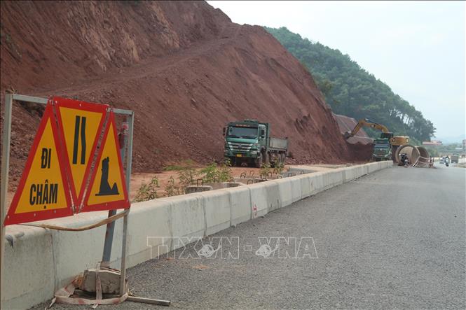 Các nhà thầu huy động máy, nhân công xử lý phần nền, móng để rải thảm nhựa. Ảnh: Quang Duy - TTXVN

