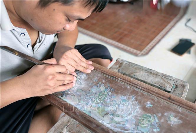 Các nghệ nhân đang chỉnh, hoàn thiện cho bức tranh. Ảnh: Trần Việt - TTXVN