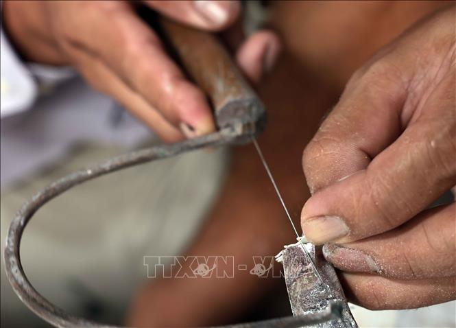 Các nghệ nhân cắt vỏ trai, ốc - nguyên liệu để làm nên tranh khảm trai. Ảnh: Trần Việt - TTXVN