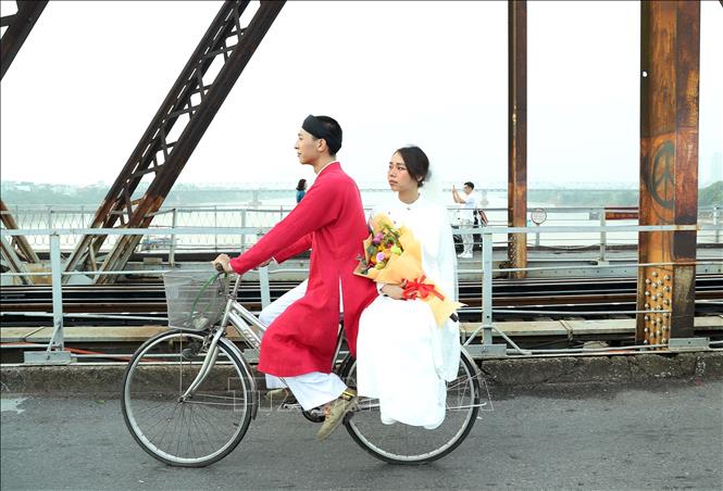 Hai bạn trẻ thướt tha, hạnh phúc trên cây cầu di sản Long Biên. Ảnh: Quốc Khánh - TTXVN