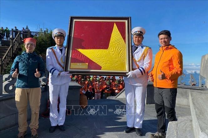 Đại diện Khu du lịch Sun World Fansipan Legend trao tặng đoàn khách du lịch lá cờ kỷ niệm, được đóng khung trang trọng, ý nghĩa. Ảnh: Sun Group/TTXVN phát