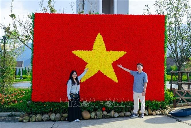 Du khách check-in với lá cờ Tổ quốc được trang trí bằng hoa tươi tại Khu du lịch Sun World Fansipan Legend. Ảnh: Sun Group/TTXVN phát