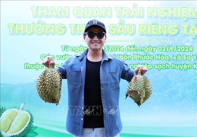 Du khách thích thú chụp hình lưu niệm với quả sầu riêng. Ảnh: Hoài Thu - TTXVN