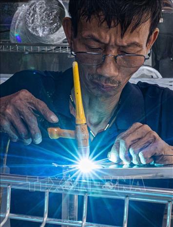 A tinsmith welds his work at Hang Thiec Street. VNA Photo: Hoàng Hiếu 