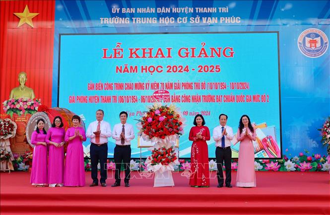 Đại diện lãnh đạo Thành ủy, UBND, Sở Giáo dục Hà Nội tặng hoa chúc mừng nhà trường. Ảnh: Thanh Tùng - TTXVN