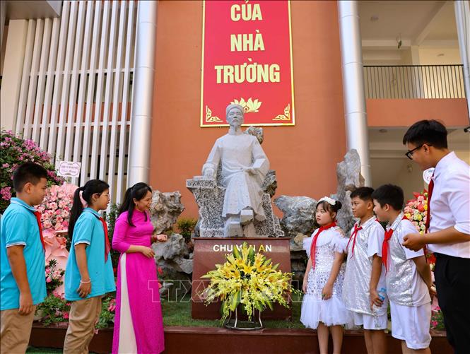 Học sinh và giáo viên bên tượng danh nhân, nhà giáo Chu Văn An được đặt trong khuôn viên trường THCS Vạn Phúc (Thanh Trì). Ảnh: Thanh Tùng - TTXVN