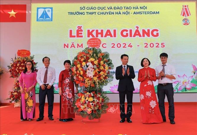 Bộ trưởng Bộ Thông tin và Truyền thông Nguyễn Mạnh Hùng tặng lẵng hoa chúc mừng Ban giám hiệu trường THPT Chuyên Hà Nội - Amsterdam. Ảnh: Hoàng Hiếu - TTXVN