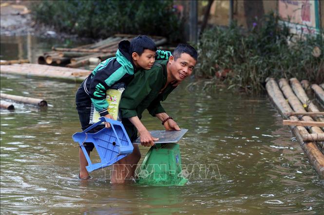 Phụ huynh cõng con qua khu vực ngập lụt để tiếp tục di chuyển khoảng 9 km đến điểm trường học tạm dự Lễ khai giảng năm học mới 2024 - 2025. Ảnh: Quang Quyết - TTXVN