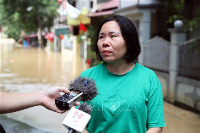 Chị Nguyễn Thị Tuyết ở thị trấn Đồng Mỏ, huyện Chi Lăng chia sẻ về diễn biến nước lũ dâng cao trong đêm gây ngập nhà, thiệt hại về tài sản của nhân dân. Ảnh: Văn Đạt - TTXVN