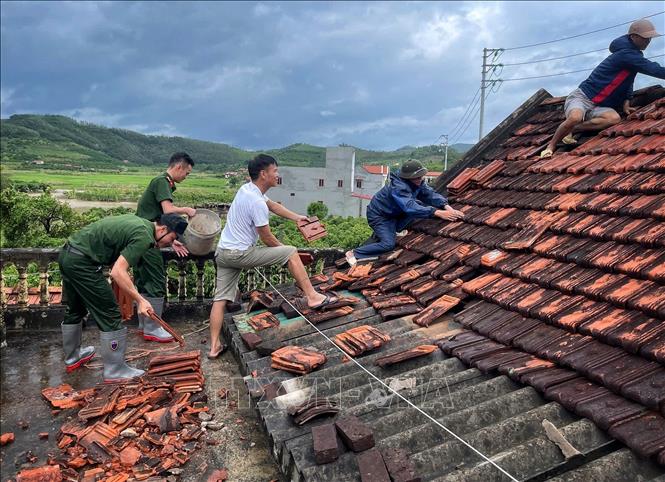 Lực lượng chức năng địa phương hỗ trợ người dân khắc phục hậu quả bão số 3. Ảnh: TTXVN phát 