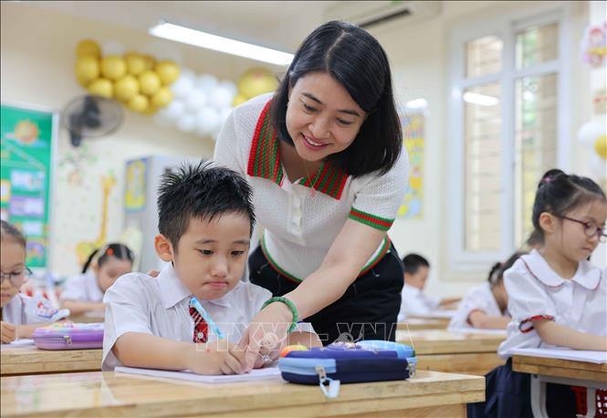 Nhà giáo Nguyễn Thị Bình Minh, Hiệu trưởng trường tiểu học Thăng Long (quận Hoàn Kiếm) ân cần bên học sinh trong ngày đầu trở lại trường khi cơn bão số 3 đi qua. Ảnh: Thanh Tùng - TTXVN 