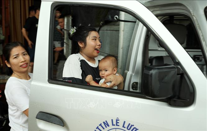 Hai mẹ con sống ở phường Lào Cai khẩn trương đi sơ tán trước sự lên nhanh của lũ sông Hồng. Ảnh: Quốc Khánh - TTXVN