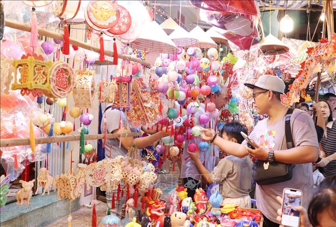 Người dân lựa chọn các mẫu lồng đèn về trang trí cho căn nhà. Ảnh: Thu Hương - TTXVN