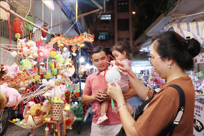 Nhiều gia đình đưa con nhỏ tới phố lồng đèn để tham quan, mua sắm. Ảnh: Thu Hương - TTXVN