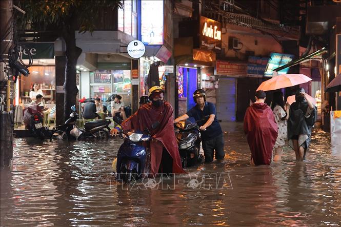 Nước ngập sâu khiến nhiều xe bị chết máy phải dắt bộ. Ảnh: Hoàng Hiếu - TTXVN
