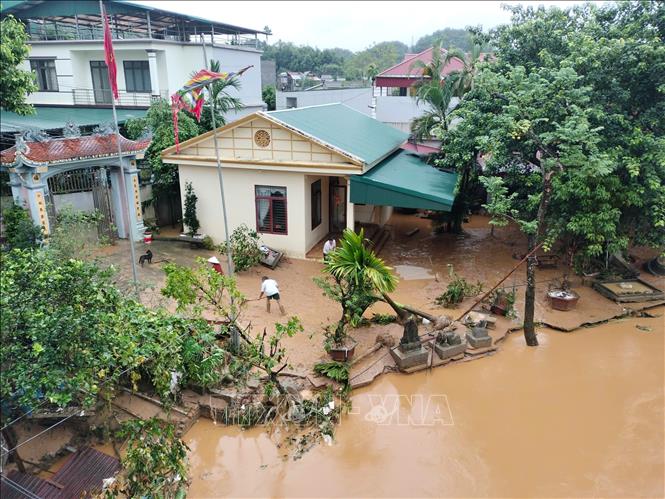 Người dân ở tổ 4, phường Minh Tân, tranh thủ dọn dẹp khi nước rút. Ảnh: Tuấn Anh - TTXVN