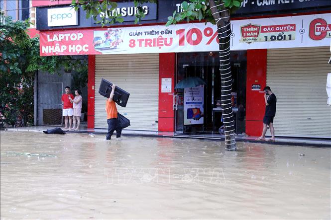 Người dân di chuyển tài sản đến nơi khô ráo. Ảnh: Quang Cường - TTXVN