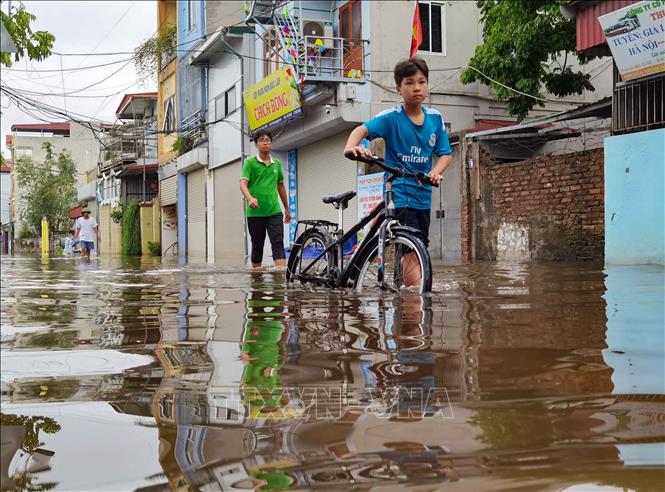 Người dân lội nước bì bõm di chuyển trong trung tâm xã. Ảnh: Thanh Tùng - TTXVN