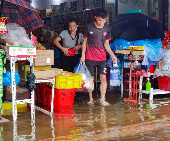 Người dân lội nước đi mua nhu yếu phẩm đề phòng nước rút chậm. Ảnh: Thanh Tùng - TTXVN