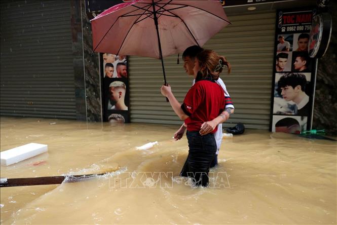 Khoảnh khắc lãng mạn của đôi bạn trẻ trong dòng nước lũ trên phố Thanh Yên, phường Phúc Tân, quận Hoàn Kiếm (ảnh chụp lúc 14h05 ngày 11/9). Ảnh: An Đăng-TTXVN