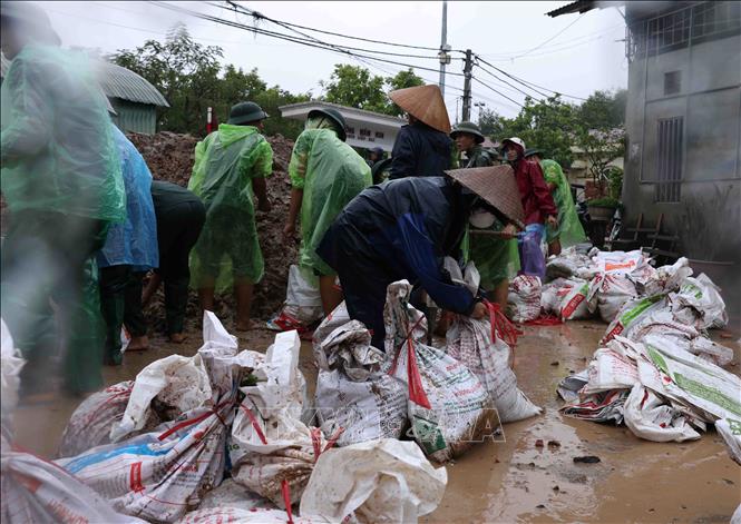 Bộ đội và người dân thôn Liệp Mai, xã Ngọc Liệp, huyện Quốc Oai khẩn trương chuẩn bị các bao tải chứa đất để gia cố đoạn đê bao sông Tích. Ảnh: Vũ Sinh - TTXVN