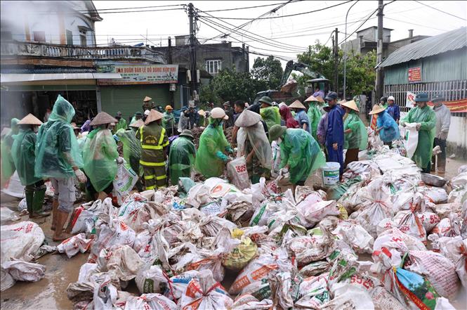 Bộ đội và người dân thôn Liệp Mai, xã Ngọc Liệp, huyện Quốc Oai khẩn trương chuẩn bị các bao tải chứa đất để gia cố đoạn đê bao sông Tích. Ảnh: Vũ Sinh - TTXVN