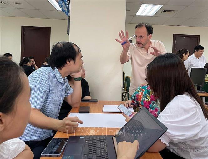 Nhà báo Alain Gérard trao đổi với các học viên về phương thức tổ chức một bài báo hiện đại trên trang thông tin điện tử với các phóng viên, biên tập viên của Thông tấn. Ảnh: TTXVN