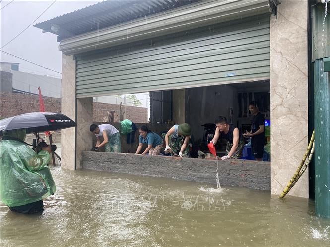 Chiến sĩ cùng người dân thôn Liệp Mai gấp rút xây tường chắn nước tràn vào nhà. Ảnh: Vũ Sinh - TTXVN